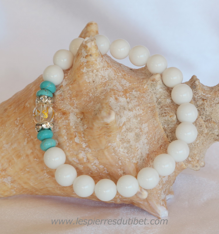 Un joli bracelet très féminin où la perle-charme, de Cristal de roche, est gravée du Mantra Universel. Éclairée par les deux perles à décor de brillants. Raffiné, gracieux, la couleur joyeuse les petites perles turquoise apporte sa fraîcheur à l'ensemble.