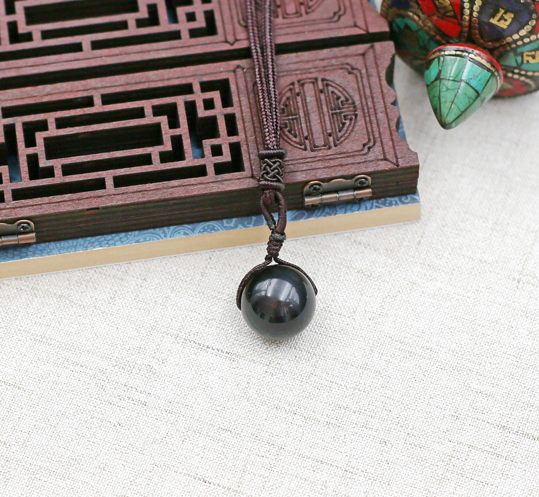 Sympathique alliance macramé de soie et grosse perle Obsidienne Œil céleste diamètre de la perle 18mm. Collier-pendentif réglable par coulissant horizontal, exécution raffinée de fins motifs de tressage traditionnel.
