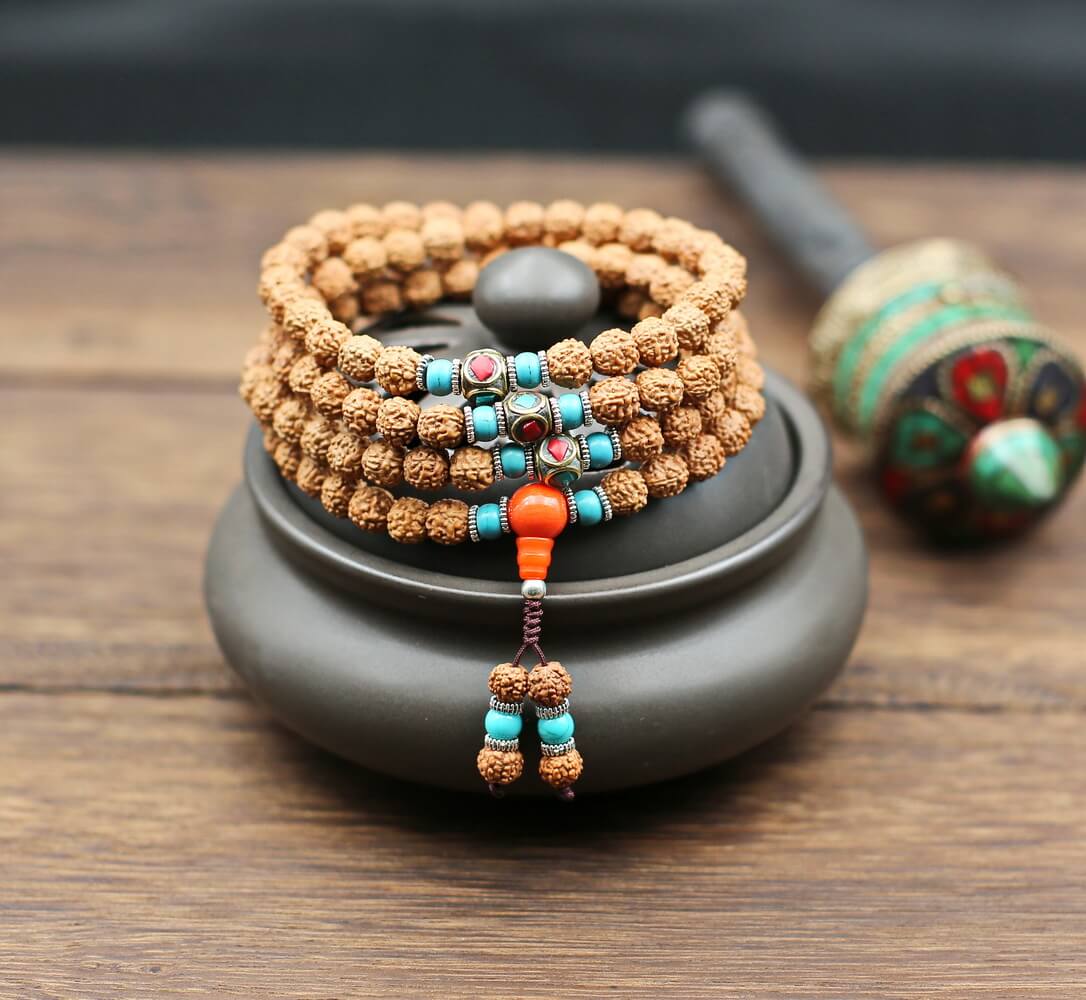 Ce fin mala de perles de graines Rudraksha montage classique du chapelet tibétain aux 108 perles porte les couleurs traditionnelles les bijoux tibétains. La couleur corail associée au bonheur, la couleur turquoise associée aux bienfaits;