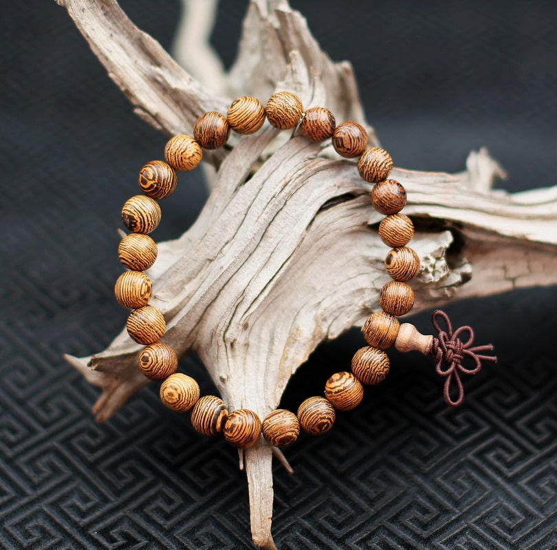 Dans ce fin bracelet mala, c'est le bois de l'arbre lui-même qui est utilisé pour le tournage des perles. Le bois est choisi spécialement afin de figurer des cercles concentriques symboles d'infini et d'éternel recommencement ou Samsara (​mot signifiant e