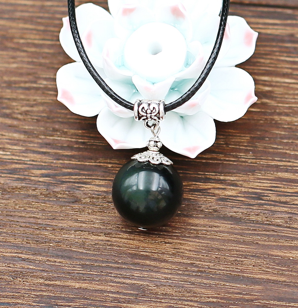 Joli montage pour cette belle perle Obsidienne Œil céleste Diamètre de la perle 18mm. Traversée d'un fil de cuivre argenté et ornée d'une jolie collerette ouvragée et d'une fine perle motif tibétain accrochée un solide cylindre-passant,