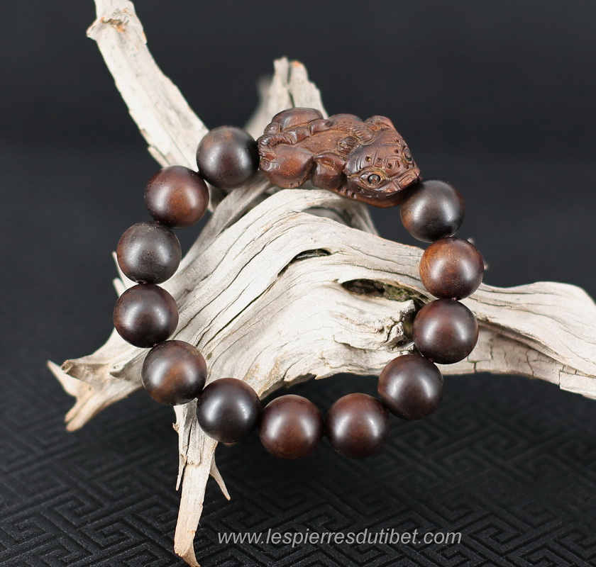 Joli bracelet magique contre-charme, composé de perles de bois de Jujubier, et orné d'une amulette du même bois, représentant le Lion des Neiges, animal sacré symbole de souveraineté et de protection.