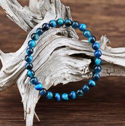 Ce fin bracelet composé de perles de pierre Oeil de tigre colorées de couleur queue de Paon, couleur au fort symbole de guérison, dans la tradition du Bouddhisme Tibétain.