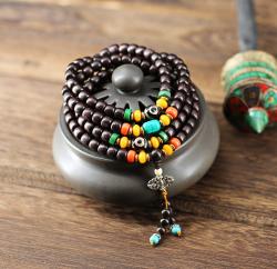 Ce Chapelet Mala composé de perles moyennes de bois d'Ébéne et orné de perles couleur turquoise ambre tibétain et corail traditionnelles, de deux perles magiques Dzi contre le mauvais sort pour le comptage dans la récitation des mantras.