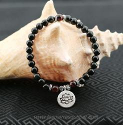 Joli bracelet ​​​d'inspiration ethnique créé par mes soins. Perles de pierre Obsidienne Oeil célèste et trois perles de Oeil de Taureau, agrémentées d'accessoires de métal argenté dont sa pendeloque ornée de la Fleur de Lotus;