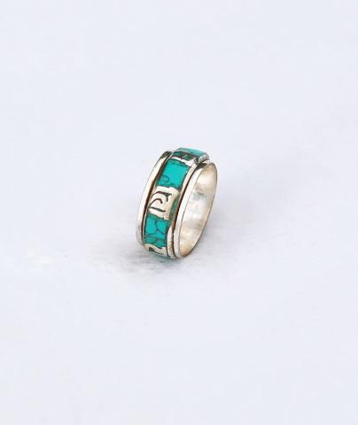 L'anneau tournant revêtu de Turquoise et orné du symbole Om Mani: porte-bonheur universel est exécuté en argent tibétain les caractères sont découpés à la main.