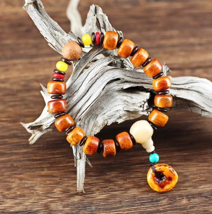 Joyeux bracelet mala tibétain composé de perles cylindriques d’os de yack à la jolie patine chaude. Séparées par de petites perles plates et trois perles de couleur, les deux perles principales sont en résine noble, et le pendant est une rondelle épaisse