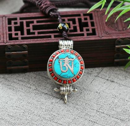 Collier Pendant protection tibétain, couvercle orné d’émail, réalisant un motif protecteur, représentant le Mantra OM bouddhiste, gage de Paix Universelle et d'équilibre. Orné de perles corail et d'une perle d'Onyx gravée le Mantra OM MANI.