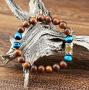L'équipement de cet imposant bracelet est composé de grosses perles bois de Kamagong et pierre Œil de Tigre Bleu guérisseur. Kamagong c'est un bois au grain très fin, au toucher soyeux, aimable à porter, dont les couleurs en camaïeu de bruns incitent à un